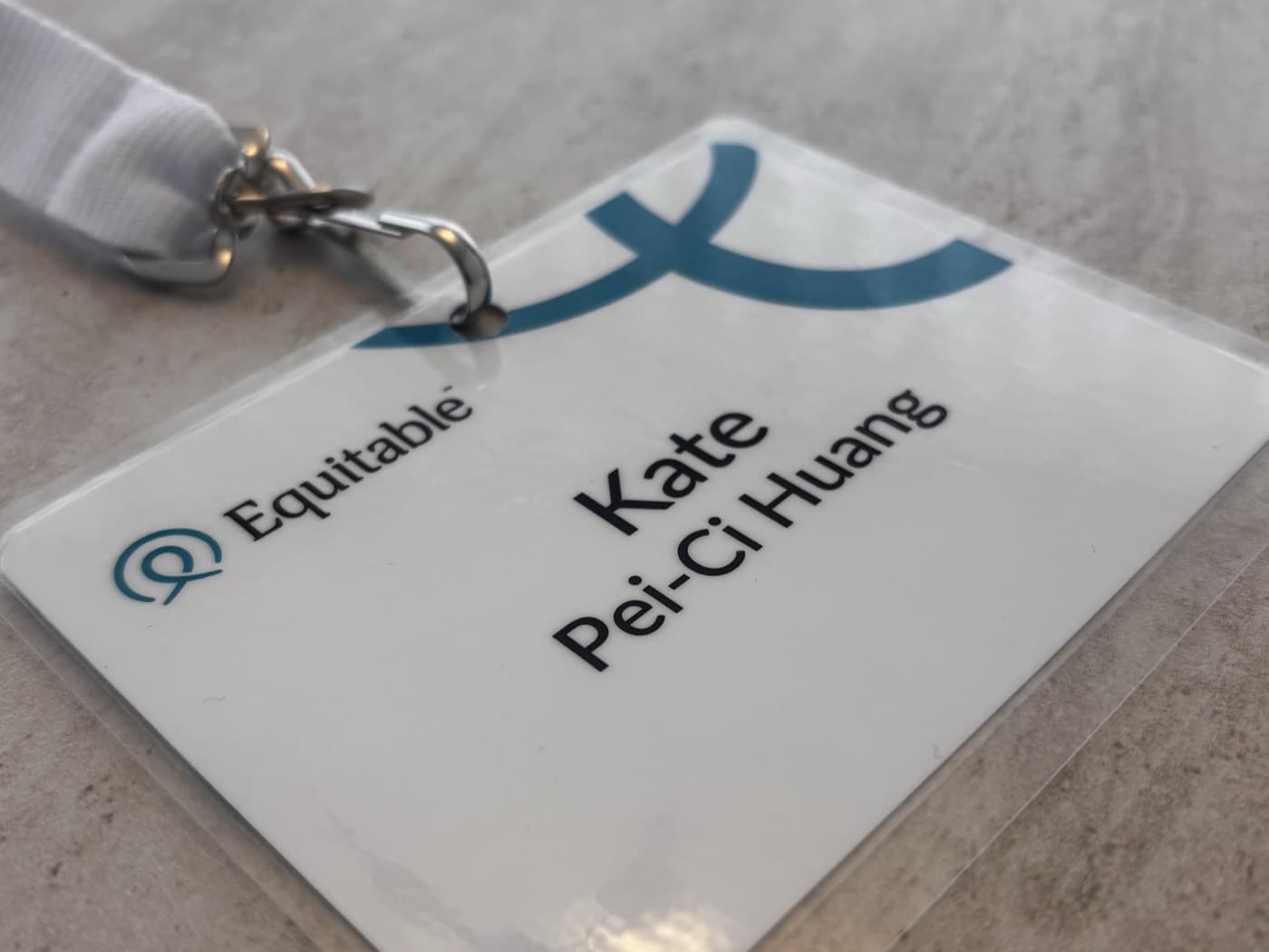 An Equitable Life employee badge on a white lanyard, resting on a stone surface.